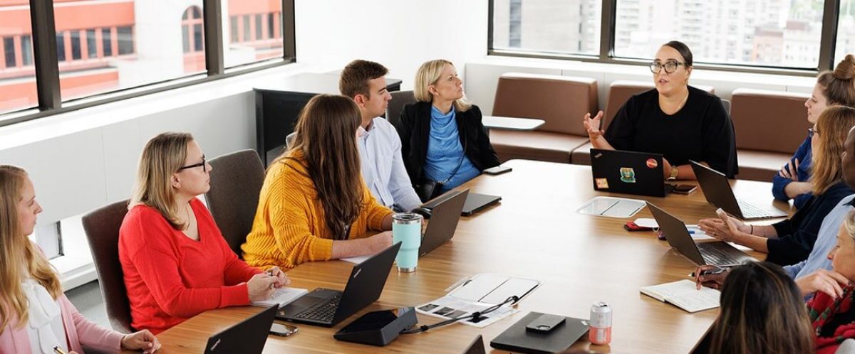 Conference Room full of employees listening to a leader speaking